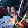 baby, car_seat, blanket, toy, pacifier, pink, fuzzy_jacket, infant, car_interior, seatbelt, child, red_toy, checkered_blanket, plush, person, cute, indoor, safety_strap, car_accessory, clothing