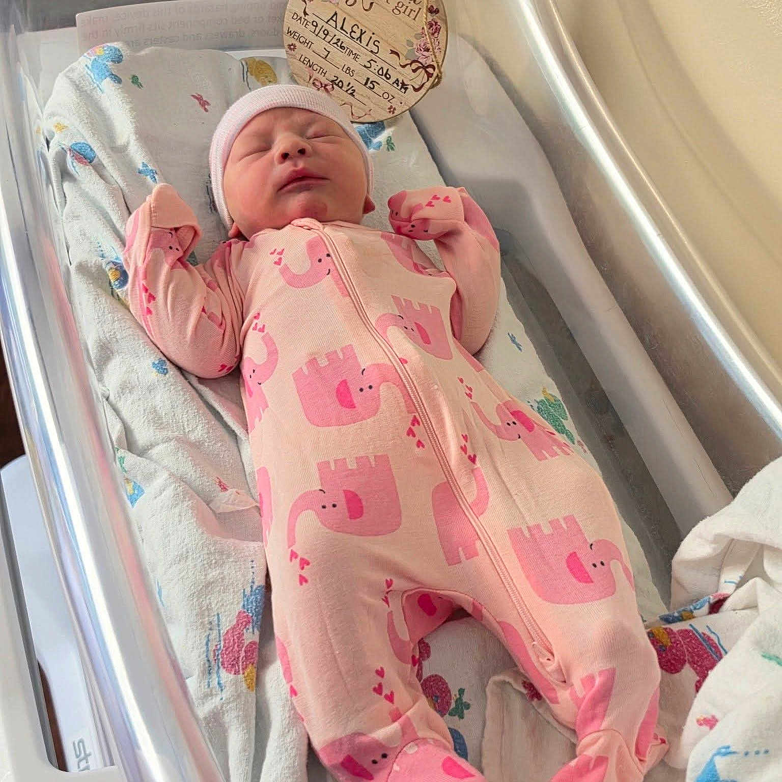 Alexis joined the competition — help win amazing prizes! newborn, baby, infant, sleeping, pink, onesie, elephant_pattern, hat, bassinet, crib, blanket, nursery, hospital, birth_announcement, portrait, face, hands, zipper, indoors, cozy