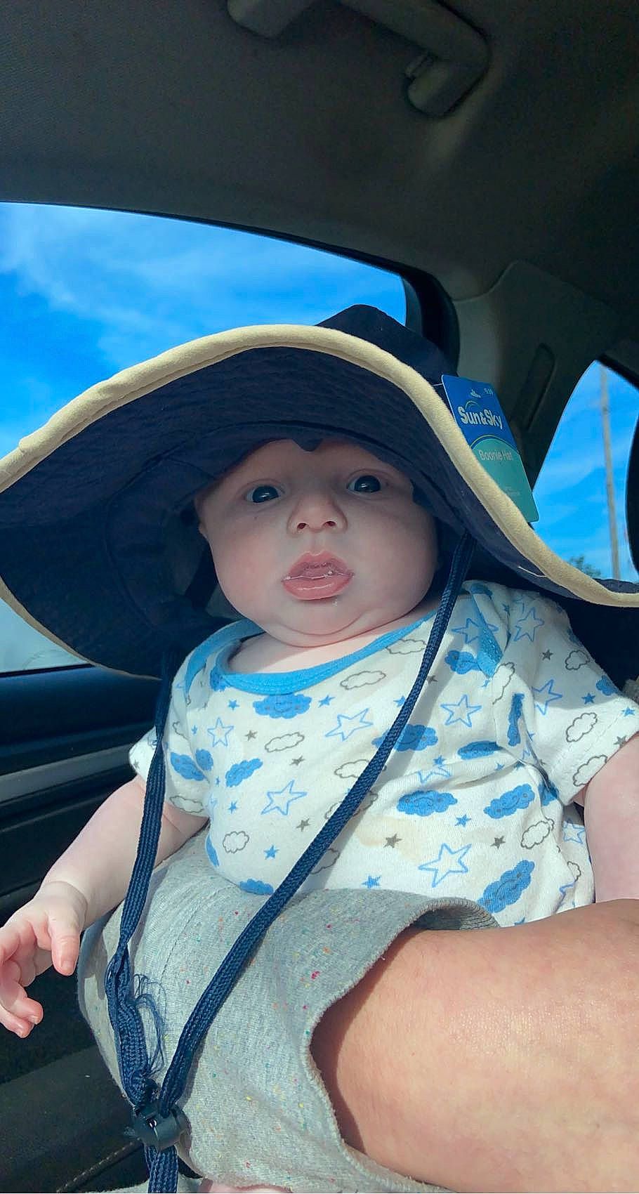 Bradley is registered to the contest to win money with this photo: automotive_exterior, automotive_lighting, azure, baby, baby_toddler_clothing, chin, cool, eye, fun, hat, headgear, headwear, iris, lip, mouth, person, product, skin, sun_hat, toddler