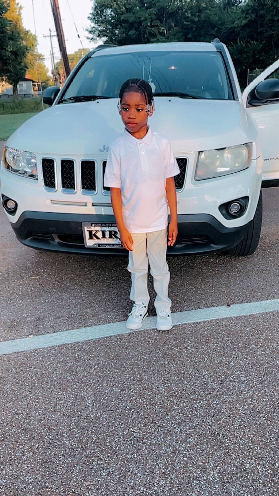 Ezekiel joined the competition — help win amazing prizes! braided_hair, calm_expression, car, casual_clothing, child, daylight, jeep, open_car_door, outdoor, parking_lot, pavement, person, road, sneakers, standing, tree, utility_pole, vehicle, white_car, white_polo_shirt