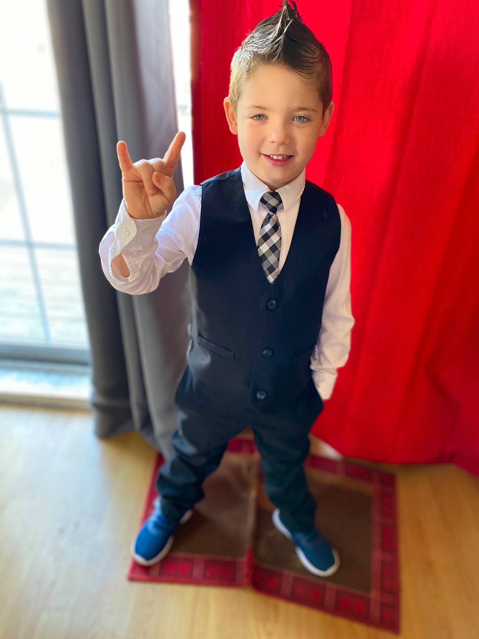 Brayden is registered to the contest to win money with this photo: child, finger, flooring, footwear, formal_wear, gesture, happy, joy, outerwear, person, shoe, standing, suit, thumb, toddler, tuxedo