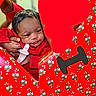 baby, infant, red_clothing, face, hand, floral_pattern, wrapping_paper, heart_shape, love, gift_wrap, cute, portrait, person, celebration, holiday, holding, closeup, indoors, expression, smile