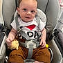 Tommy a rejoint le concours — aidez-le/la à gagner de superbes lots ! baby, child, car_seat, seatbelt, plush_toy, white_shirt, brown_pants, striped_socks, smiling, indoors, cute, infant, person, happy, toddler, clothing, seat, baby_toy, safety_harness, portrait