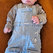 Tommy participe au concours pour gagner de l'argent avec cette photo : baby, child, infant, overalls, cap, lying_down, brown_background, plush_toy, grey_shirt, cute, tongue_out, warm_clothing, small_hands, face, headwear, footwear, pocket, closeup, indoor, soft_texture