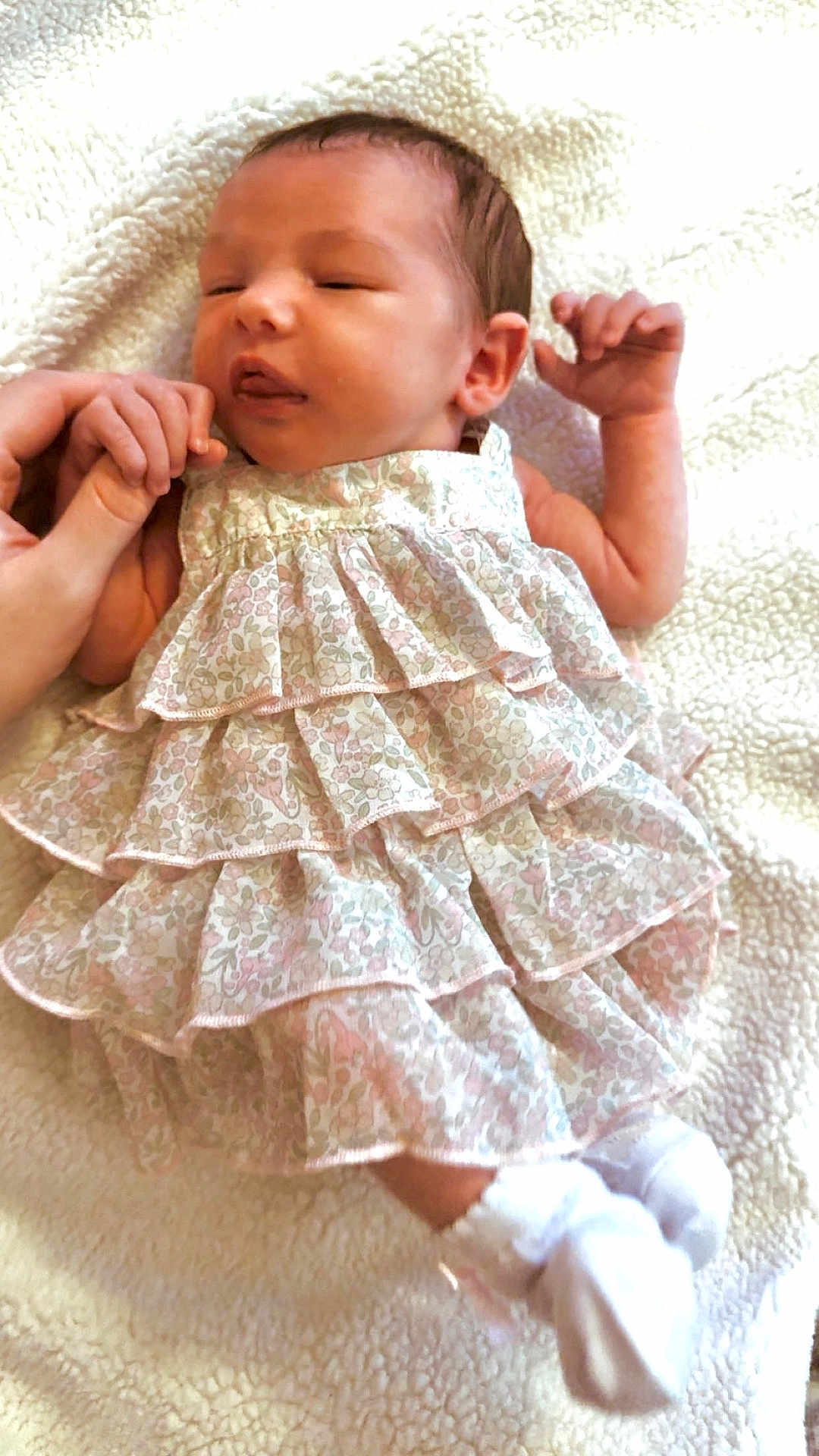 Raelynn is registered to the contest to win money with this photo: newborn, baby, infant, sleeping, hand_holding, dress, floral, ruffles, white_socks, blanket, soft_texture, cute, peaceful, portrait, close_up, person, skin, head, face, resting