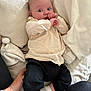 baby, infant, child, person, clothing, pillow, blanket, socks, hand, comfort, home, indoor, cute, lying_down, young, soft, casual_wear, expression, support, resting