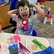 Olivia joined the competition — help win amazing prizes! child, girl, minion_goggles, birthday, party, table, juice_box, party_favor, straw, decorations, ribbon, blue_chair, boy, classroom, carpet, window, toy_house, colorful, celebration, happy