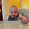 baby, high_chair, food, messy, bib, smile, face, child, indoor, light, hand, table, cute, fun, happy, infant, feeding, clothing, person, portrait