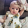 baby, child, girl, plush_toy, bunny, headband, bow, dress, floral_pattern, couch, blanket, indoor, portrait, cute, expression, person, young_child, sitting, soft_toy, casual