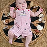 baby, infant, child, romper, striped_clothing, nautical_theme, seashells, woven_mat, floor, curious_expression, raised_fists, cute, portrait, lying_down, indoors, soft_lighting, skin, person, head, legs