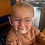 Kohen joined the competition — help win amazing prizes! baby, brown, child, clothing, cozy, cute, eyewear, face, glasses, happy, head, indoor, person, portrait, seat, sitting, smiling, table, toddler, wood