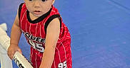 Aiden is registered to the contest to win money with this photo: toddler, child, red_jersey, indoor, blue_floor, plastic_bar, barefoot, young_child, curious, sportswear, play_area, person, standing, short_hair, white_bar, grip, active, casual, focus, exploration