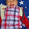 toddler, child, smiling, laughing, portrait, lying_down, plaid_shirt, red_jacket, blue_blanket, stars, outdoor_style, happy, face, head, clothing, infant, playful, close_up, photography, family