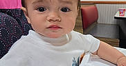 Aiden joined the competition — help win amazing prizes! booth_seating, casual, child, colorful, curious, cute, expression, face, hand, high_chair, indoor, orange, portrait, restaurant, seated, table, toddler, wall_art, white_shirt, young_child