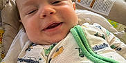 Ledger joined the competition — help win amazing prizes! baby, infant, smiling, onesie, car_print, green_trim, cushion, seat, indoors, window, natural_light, face, cheeks, happy, child, clothing, cute, portrait, relaxing, home