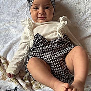 Inaya a rejoint le concours — aidez-le/la à gagner de superbes lots ! baby, infant, headband, bow, houndstooth_pattern, blanket, white_towel, romper, long_sleeve_shirt, smile, face, feet, toes, lying_down, portrait, soft_texture, indoors, floor_tiles, cute, happy