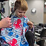 child, boy, haircut, barbershop, cape, octopus, comb, scissors, smile, happy, hair, stylist, chair, indoor, short_hair, person, kid, hairdresser, haircutting, fun