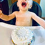 Eli joined the competition — help win amazing prizes! toddler, child, cake, high_chair, frosting, sprinkles, smiling, happy, celebration, birthday, messy, food, face, mouth_open, arms_outstretched, indoor, wooden_door, plastic_plate, white_cream, colorful_sprinkles