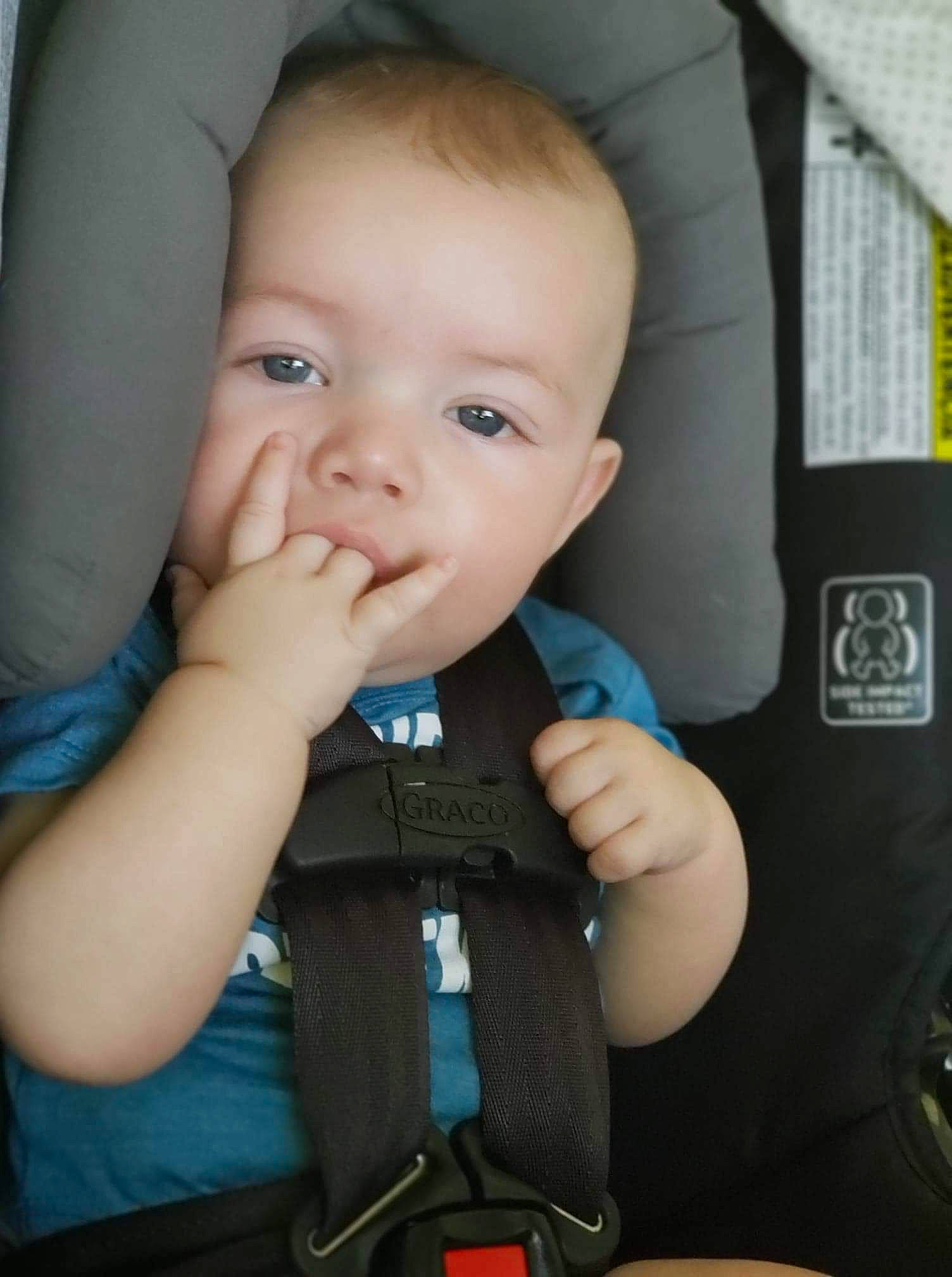 Clinton is registered to the contest to win money with this photo: auto_part, baby, baby_carriage, baby_in_car_seat, baby_products, car_seat, cheek, child, chin, eye, face, finger, hand, head, person, product, seat_belt, sitting, skin, toddler