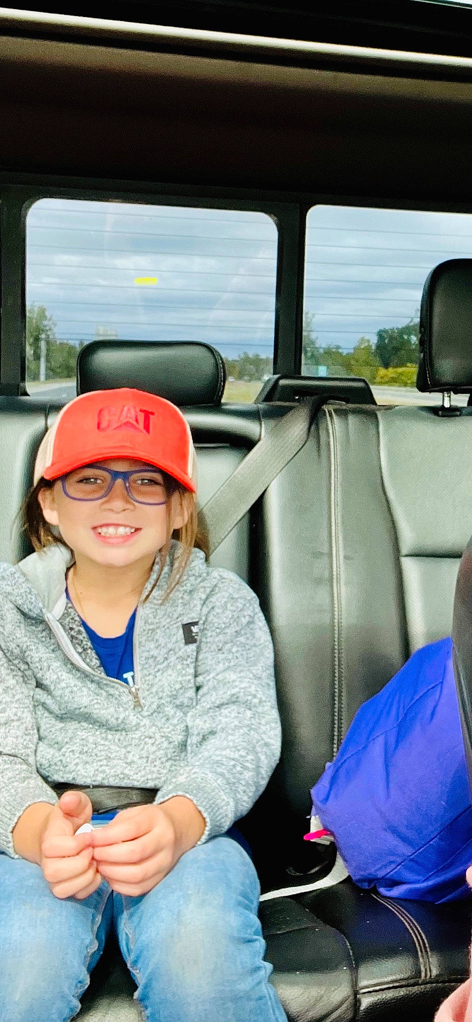 Lilyanne is registered to the contest to win money with this photo: auto_part, automotive_exterior, baseball_cap, blue, cap, cloud, family_car, fun, happy, headwear, joy, leisure, mode_of_transport, motor_vehicle, passenger, people, person, recreation, smile, travel