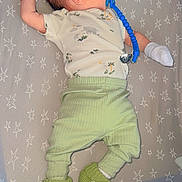 Xavier is registered to the contest to win money with this photo: baby, infant, pacifier, blue_pacifier, dinosaur_slippers, green_pants, onesie, star_pattern, crib, sleeping, cute, newborn, baby_clothes, soft_toys, bed, lying_down, white_mittens, hair_spikes, baby_accessories, child