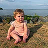 Raelynn Grace joined the competition — help win amazing prizes! toddler, child, baby, outdoor, grass, rocks, water, sky, clouds, dress, curly_hair, blue_eyes, earrings, sunlight, nature, summer, portrait, sitting, cute, daytime