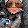 baby, child, sunglasses, bandana, pacifier, baby_carrier, smile, face, leather_jacket, outdoor, person, fashion, cute, headwear, accessory, closeup, happy, young_child, casual, portrait