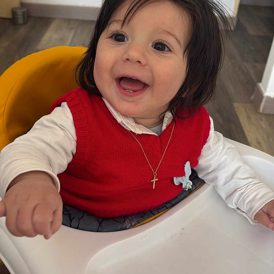 Dylan participe au concours pour gagner de l'argent avec cette photo : baby, child, smiling, high_chair, red_sweater, necklace, cross, happy, indoor, person, toddler, long_sleeve, dark_hair, wood_floor, white_wall, furniture, cute, portrait, small_child, seated