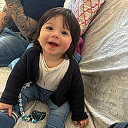 Dylan participe au concours pour gagner de l'argent avec cette photo : toddler, child, smiling, jeans, cardigan, white_shirt, pacifier, name_tag, tattoos, watch, sofa, cushion, indoor, happy, cute, person, patterned_fabric, sitting, baby, family