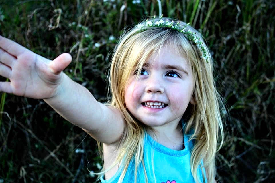 Makenna is registered to the contest to win money with this photo: blond, child, child_model, face, facial_expression, finger, fun, gesture, grass, hair, hand, happy, joy, organ, people_in_nature, person, photograph, photography, portrait, smile