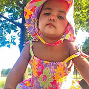 Megan is registered to the contest to win money with this photo: toddler, child, hat, floral, dress, colorful, outdoor, tree, greenery, sunlight, summer, cute, portrait, baby, person, nature, young_child, sunhat, bright, daytime