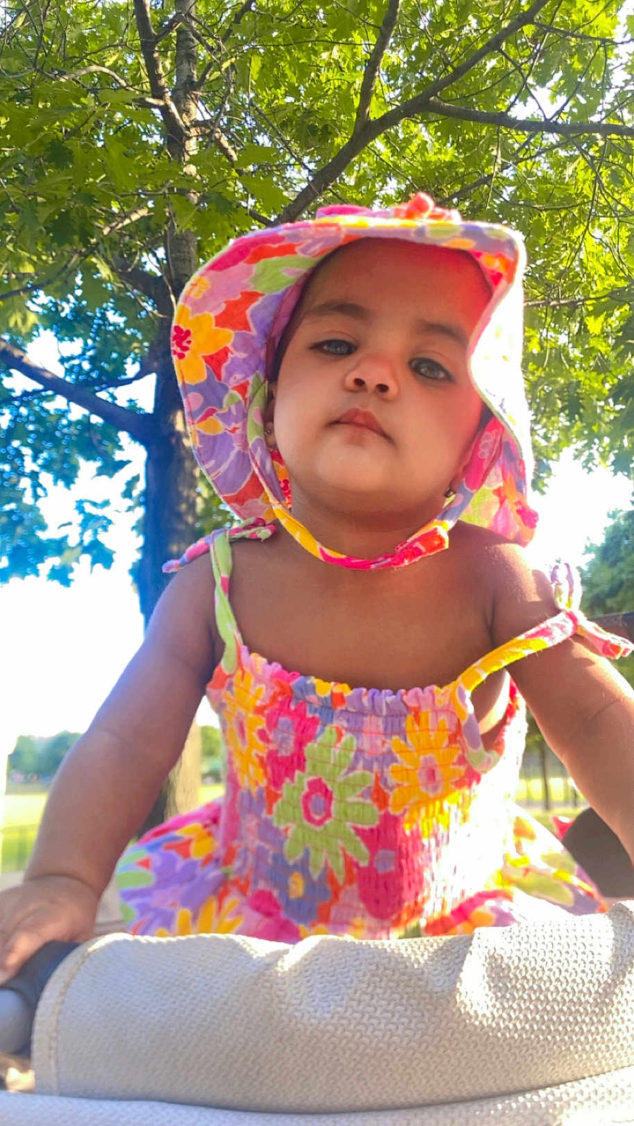 Megan is registered to the contest to win money with this photo: toddler, child, hat, floral, dress, colorful, outdoor, tree, greenery, sunlight, summer, cute, portrait, baby, person, nature, young_child, sunhat, bright, daytime
