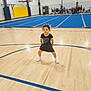 child, girl, gymnasium, cheerleader, sports, basketball_hoop, blue_mat, wooden_floor, bleachers, group, people, indoor, athletic, pose, smile, curly_hair, white_shoes, black_outfit, team, recreation
