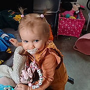 Kayssy a rejoint le concours — aidez-le/la à gagner de superbes lots ! toddler, child, pacifier, pigtails, toy, stuffed_animal, blanket, bed, clothing, indoor, poster, furniture, playroom, person, floor, pink, orange, cute, baby, smiling