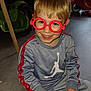 child, boy, smiling, glasses, toy, playroom, indoor, clothing, sitting, happy, plastic, red, grey, floor, furniture, game, person, young, casual, play
