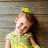 blue_eyes, bright_colors, cheerful, child, closeup, cute, fashion, glamour, hair_accessory, happy, innocence, outfit, playful, portrait, posing, smiling, sparkles, wooden_wall, yellow_dress, young_girl