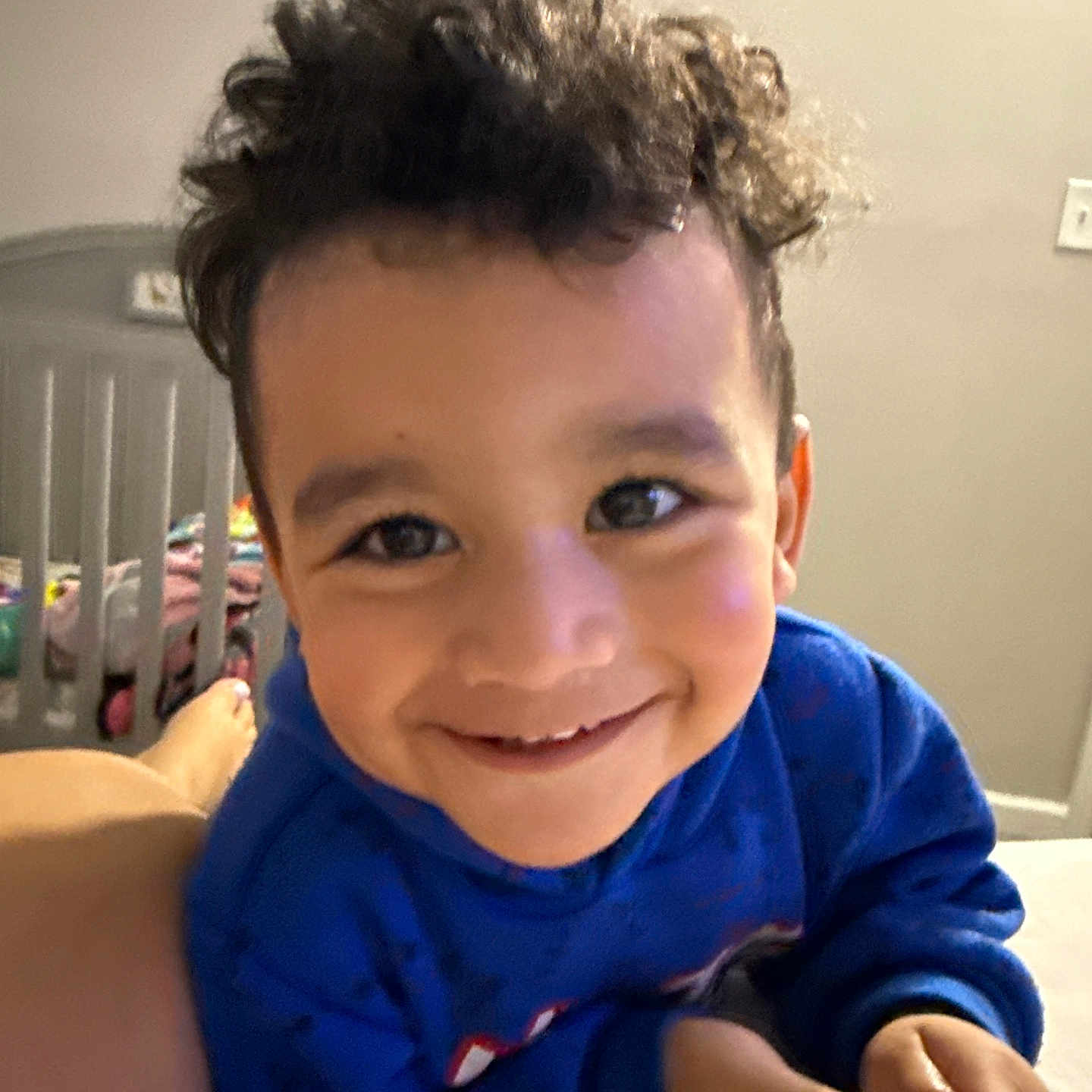 Dominic Struve joined the competition — help win amazing prizes! bedroom, blanket, blue_hoodie, child, closeup, crib, curly_hair, cute, expression, face, hand, happy, indoor, person, playful, portrait, skin, smiling, toddler, young_child