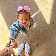 Athena joined the competition — help win amazing prizes! toddler, child, holding_hand, pink_flower, hair_accessories, denim_jacket, curious, looking_up, adult_hand, striped_skirt, white_sneakers, concrete_floor, sunlight, shadow, outdoor, person, casual_clothing, cute, young_child, hand_holding