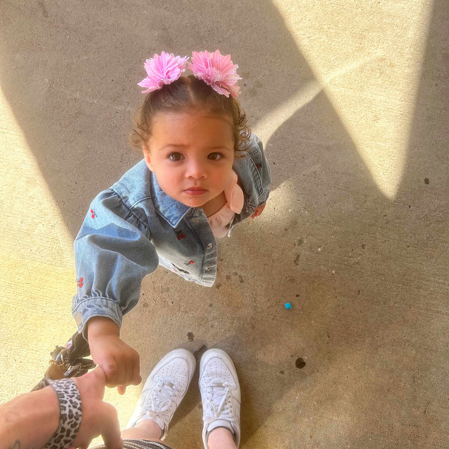 Athena joined the competition — help win amazing prizes! toddler, child, holding_hand, pink_flower, hair_accessories, denim_jacket, curious, looking_up, adult_hand, striped_skirt, white_sneakers, concrete_floor, sunlight, shadow, outdoor, person, casual_clothing, cute, young_child, hand_holding
