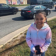 Princess joined the competition — help win amazing prizes! child, girl, smiling, braids, beads, hoodie, phone, shopping_bag, sidewalk, grass, cars, road, storefront, gamestop, daylight, outdoor, urban, street, person, happy