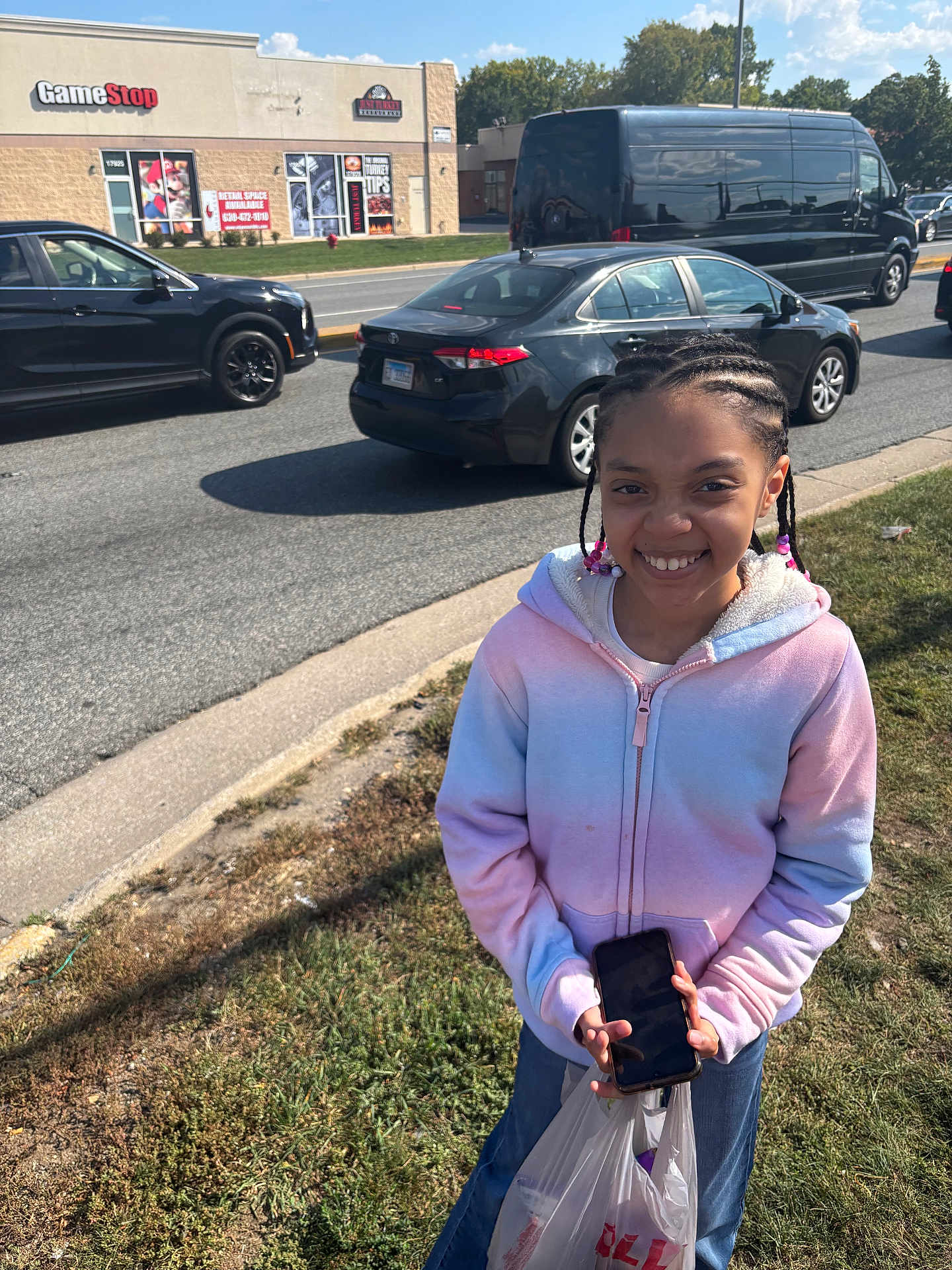 Princess joined the competition — help win amazing prizes! child, girl, smiling, braids, beads, hoodie, phone, shopping_bag, sidewalk, grass, cars, road, storefront, gamestop, daylight, outdoor, urban, street, person, happy