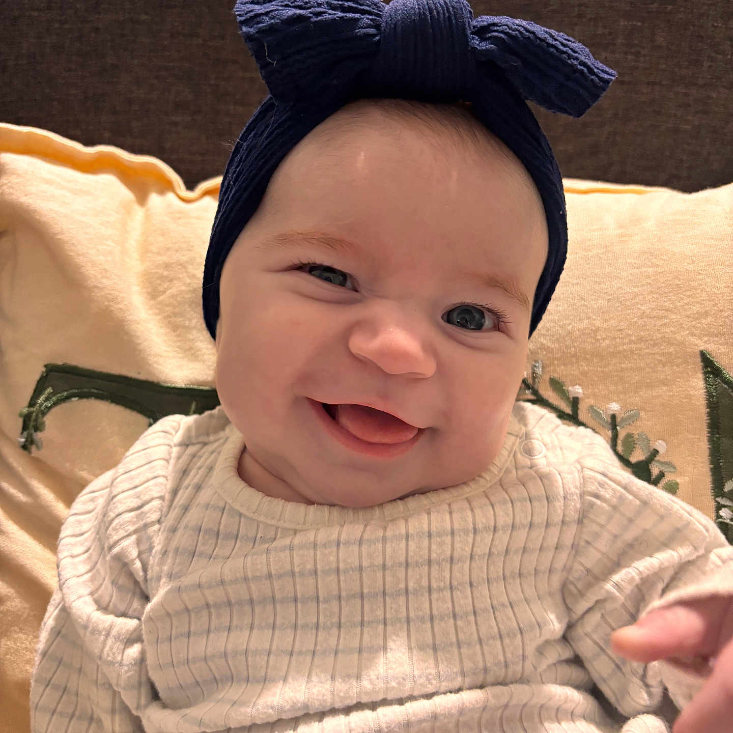 Lihana participe au concours pour gagner de l'argent avec cette photo : baby, beige, blue, bow, child, cozy, cute, embroidery, face, happy, headband, indoor, infant, person, pillow, portrait, smile, sweater, tongue, white