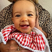 Charlie participe au concours pour gagner de l'argent avec cette photo : baby, child, smile, teeth, red_checkered_clothing, hand, adult, leopard_print, earrings, portrait, cute, happy, infant, holding, face, skin, eyes, person, closeup, apparel