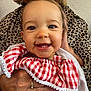 baby, child, smile, teeth, red_checkered_clothing, hand, adult, leopard_print, earrings, portrait, cute, happy, infant, holding, face, skin, eyes, person, closeup, apparel