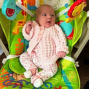 Freya is registered to the contest to win money with this photo: animal_print, baby, baby_rocker, carpet, child, colorful, comfortable, curious, cute, doll, floral_pants, indoor, infant, knitted_clothing, looking_away, pink_sweater, seated, small_hands, toys, white_socks