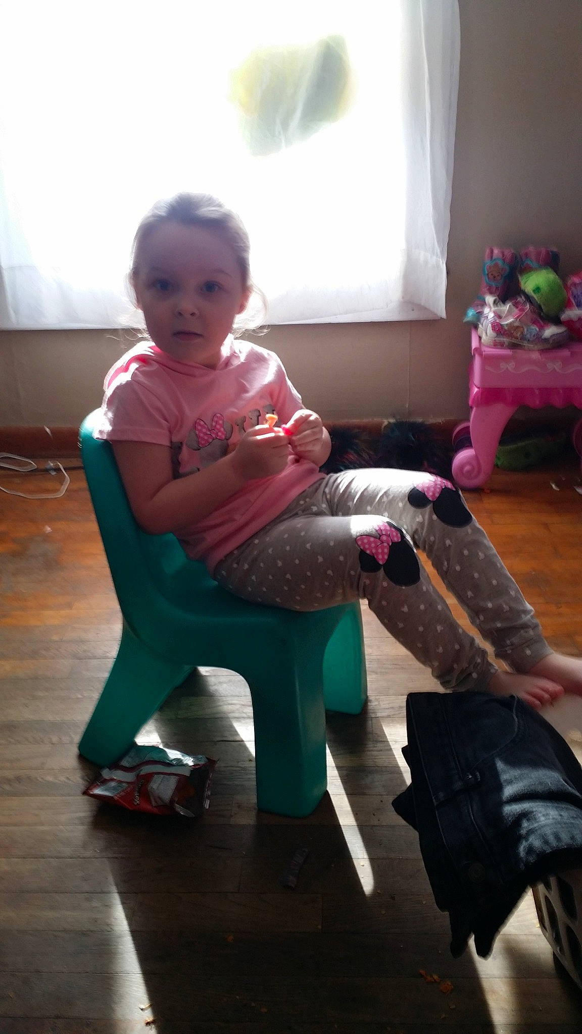 Emma is registered to the contest to win money with this photo: arm, chair, child, day, floor, flooring, footwear, fun, furniture, girl, human_body, infant, leg, person, pink, play, product, shoe, sitting, standing