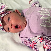 Paisley joined the competition — help win amazing prizes! baby, infant, child, yawning, headband, floral, purple, pink, clothing, onesie, bed, blanket, cute, portrait, face, skin, person, sleepy, newborn, expression