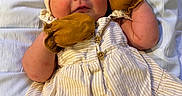 Paisley is registered to the contest to win money with this photo: baby, infant, child, mittens, headband, bow, dress, striped_clothing, lying_down, white_sheet, cute, chubby_cheeks, small_hands, soft_lighting, indoors, portrait, closeup, skin, expression, person