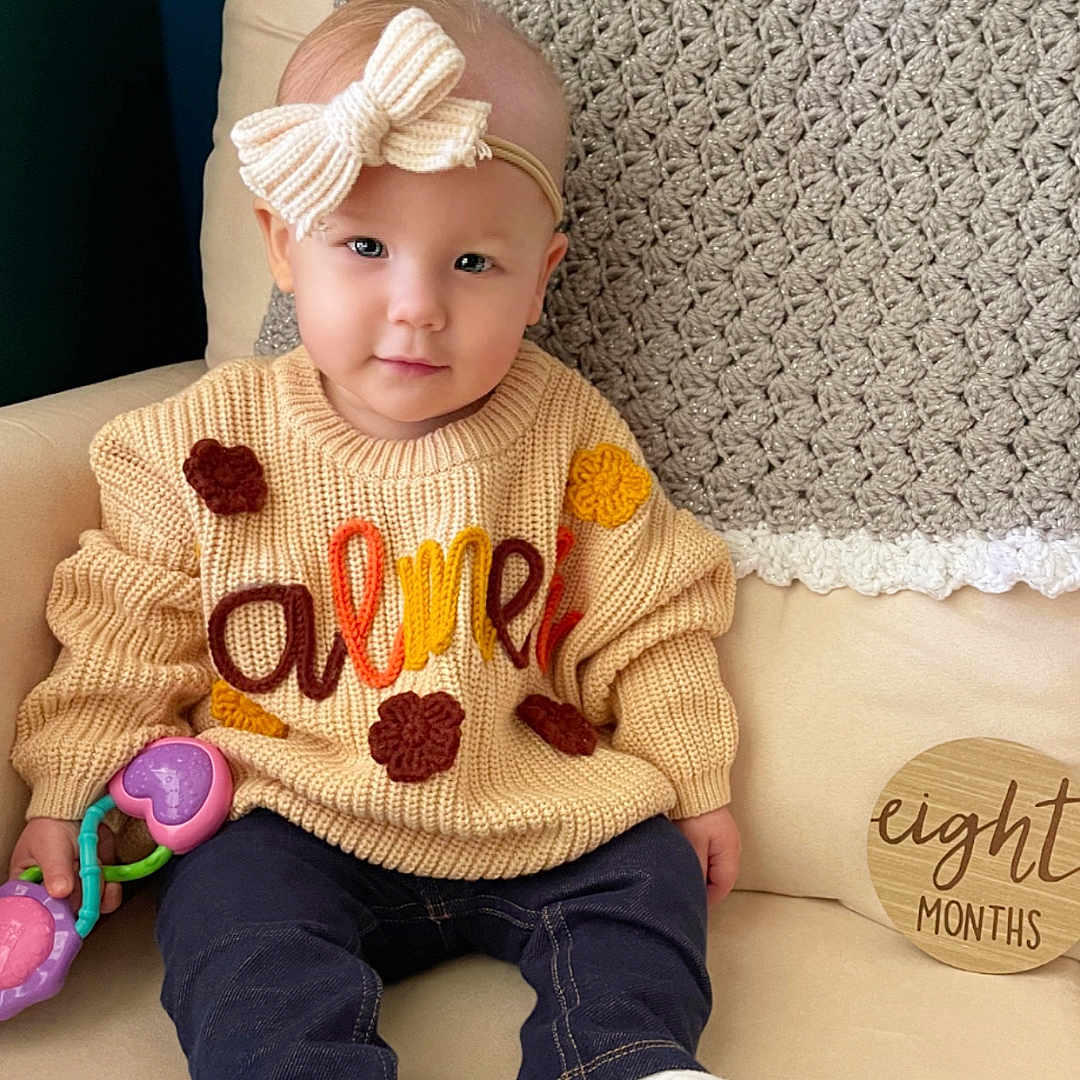 Palmer is registered to the contest to win money with this photo: baby, cap, clothing, couch, cushion, face, furniture, hat, head, homedecor, hosiery, jeans, knitwear, pants, person, photography, portrait, sitting, sock, sweater