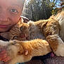 Kilo is registered to the contest to win money with this photo: person, cat, orange_tabby, pet, close_up, selfie, paw, outdoor, sunlight, nature, fur, face, nose_ring, whiskers, happy, relaxed, animal, friendship, companionship, cuddle